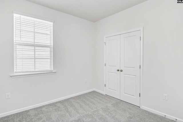 unfurnished bedroom with light colored carpet and a closet