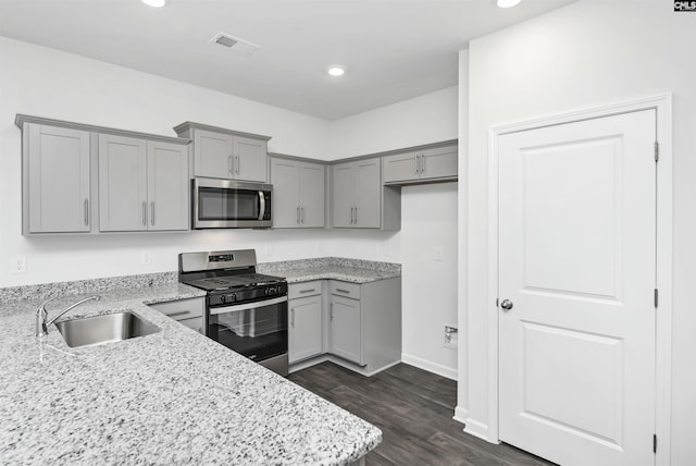 kitchen featuring dark hardwood / wood-style flooring, appliances with stainless steel finishes, sink, and light stone counters