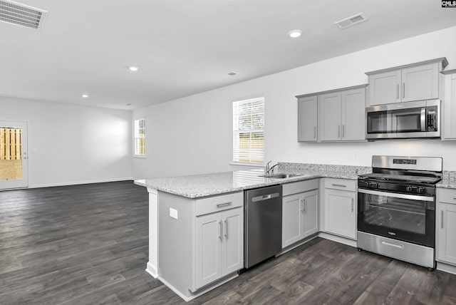 kitchen with light stone counters, sink, stainless steel appliances, and kitchen peninsula