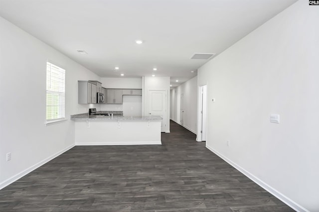 kitchen featuring range, dark hardwood / wood-style floors, kitchen peninsula, and gray cabinetry