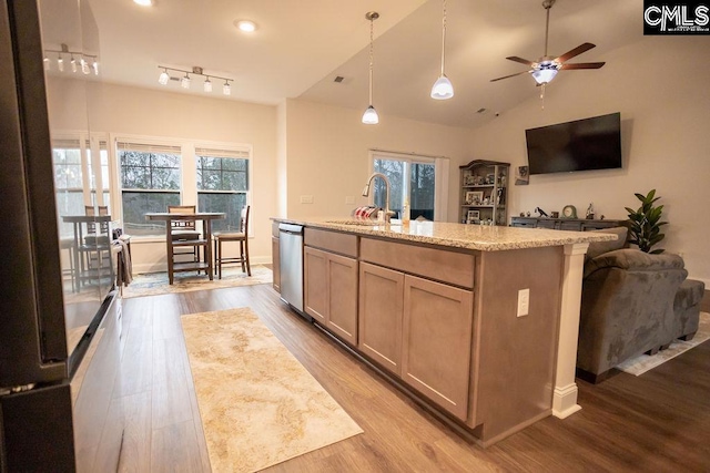 kitchen featuring sink, a center island with sink, light wood-type flooring, dishwasher, and light stone countertops