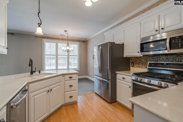 kitchen with sink, crown molding, appliances with stainless steel finishes, white cabinetry, and decorative light fixtures