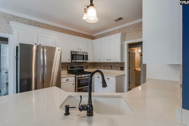 kitchen with sink, ornamental molding, appliances with stainless steel finishes, light stone countertops, and white cabinets