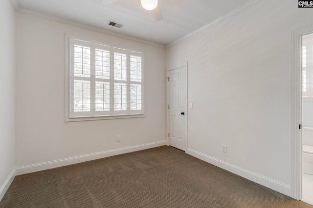 empty room featuring a healthy amount of sunlight, ornamental molding, and dark colored carpet