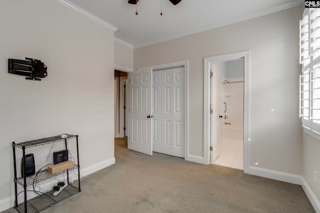 carpeted bedroom featuring ornamental molding, connected bathroom, ceiling fan, and a closet