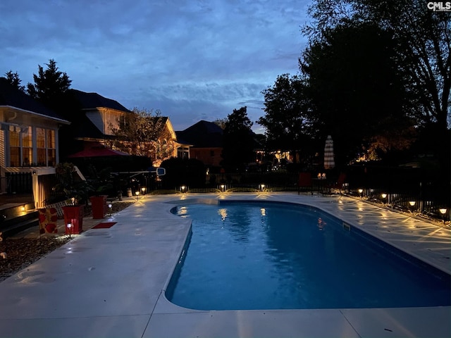 pool at dusk featuring a patio area