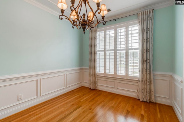 spare room featuring a notable chandelier, ornamental molding, and light hardwood / wood-style floors