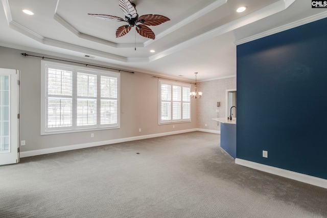 carpeted empty room featuring crown molding, a tray ceiling, and ceiling fan with notable chandelier