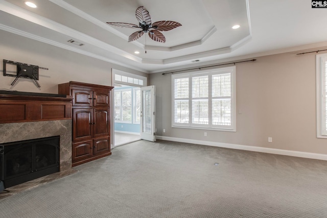 living room featuring crown molding, ceiling fan, a high end fireplace, light carpet, and a raised ceiling