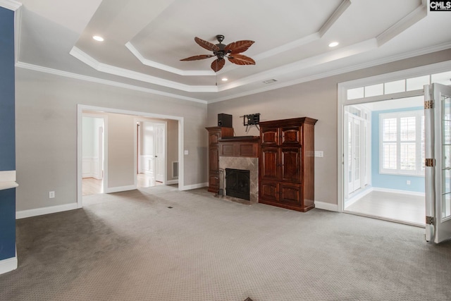 unfurnished living room with crown molding, a fireplace, a tray ceiling, and carpet flooring