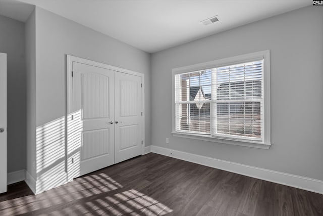 unfurnished bedroom featuring dark hardwood / wood-style flooring and a closet