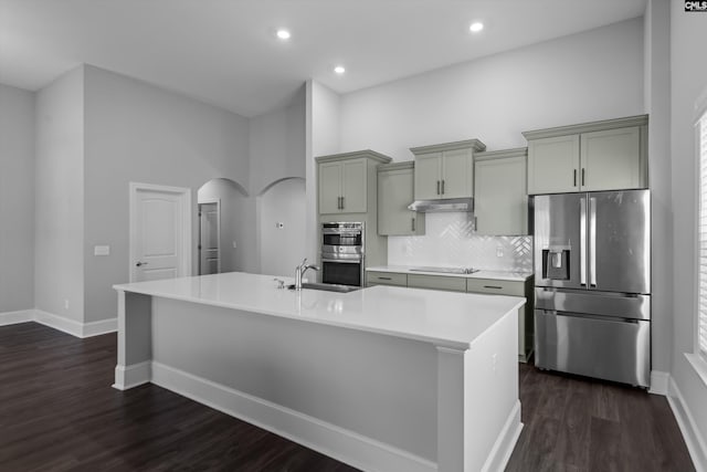 kitchen with gray cabinetry, dark hardwood / wood-style flooring, stainless steel appliances, and an island with sink