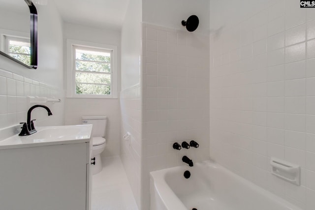 full bathroom with vanity, tiled shower / bath, tile walls, and toilet