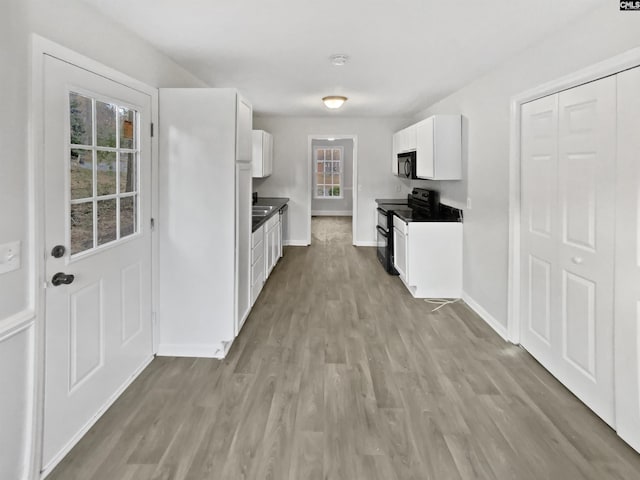 kitchen with white cabinetry, light wood-type flooring, and black appliances