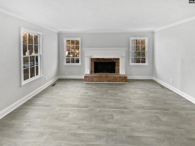 unfurnished living room with a fireplace, ornamental molding, a healthy amount of sunlight, and light wood-type flooring