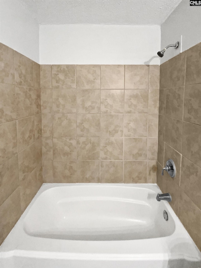 bathroom with tiled shower / bath combo and a textured ceiling