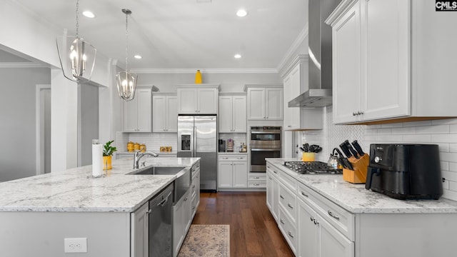 kitchen featuring appliances with stainless steel finishes, decorative light fixtures, wall chimney range hood, and white cabinets