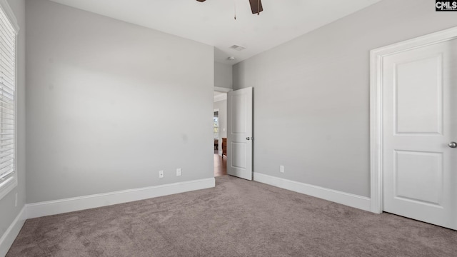 unfurnished bedroom with light carpet, multiple windows, and ceiling fan