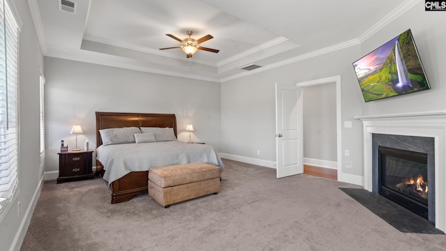 bedroom featuring a raised ceiling, ornamental molding, carpet floors, and a high end fireplace