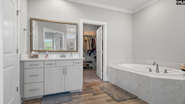 bathroom featuring vanity, tiled tub, and crown molding