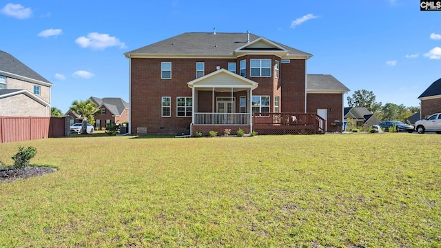 rear view of house with a lawn, a sunroom, and a deck