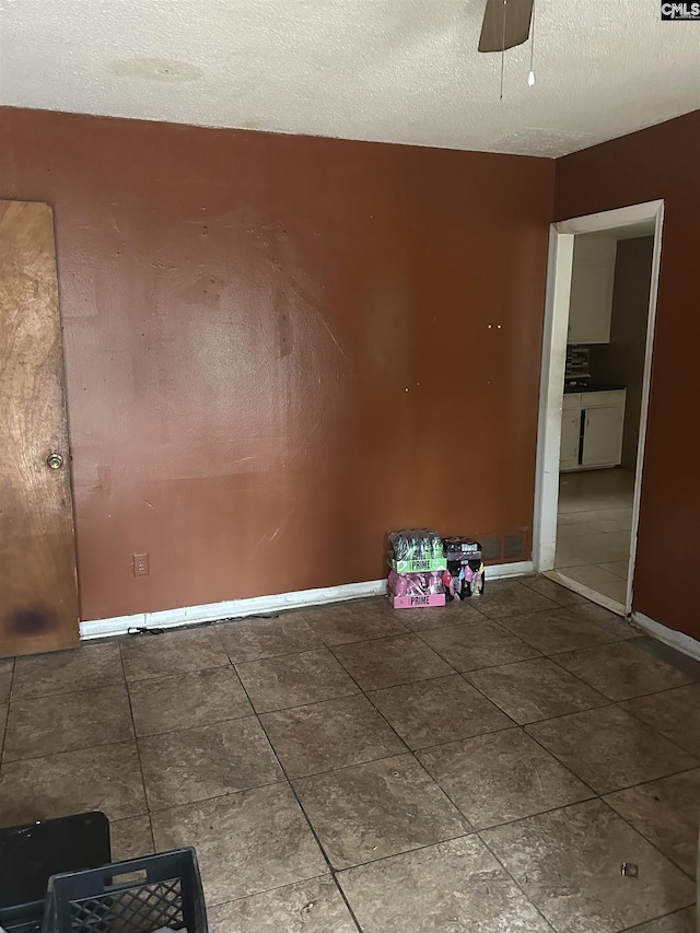 tiled spare room with ceiling fan and a textured ceiling