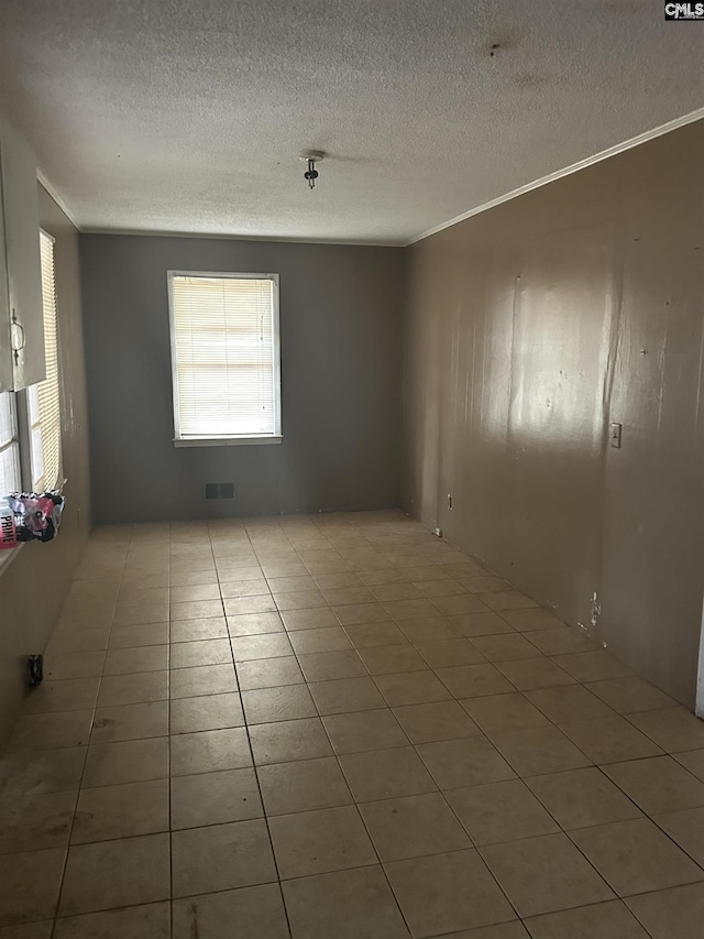 tiled spare room featuring crown molding and a textured ceiling