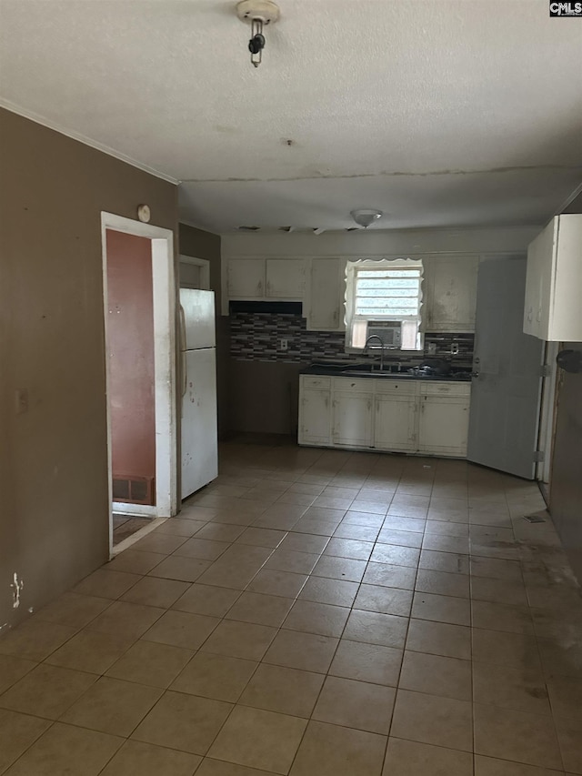 kitchen featuring sink, a textured ceiling, white fridge, white cabinets, and backsplash