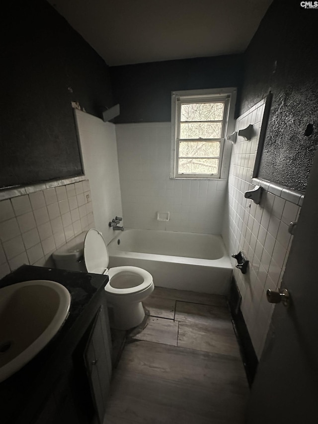 full bathroom with vanity, toilet, tiled shower / bath combo, and tile walls