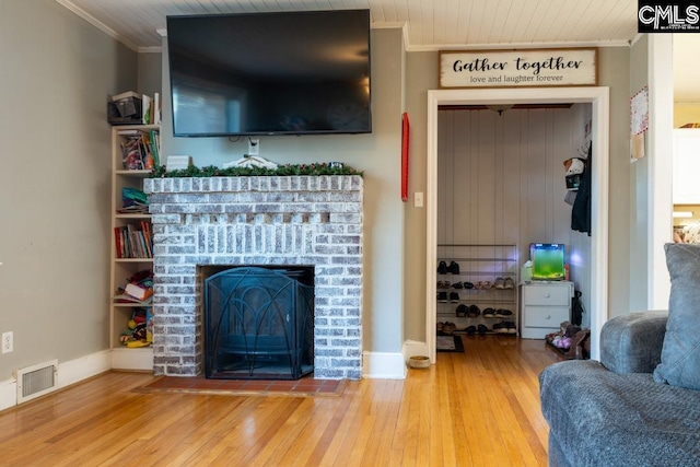 living room featuring crown molding, a fireplace, and light hardwood / wood-style flooring