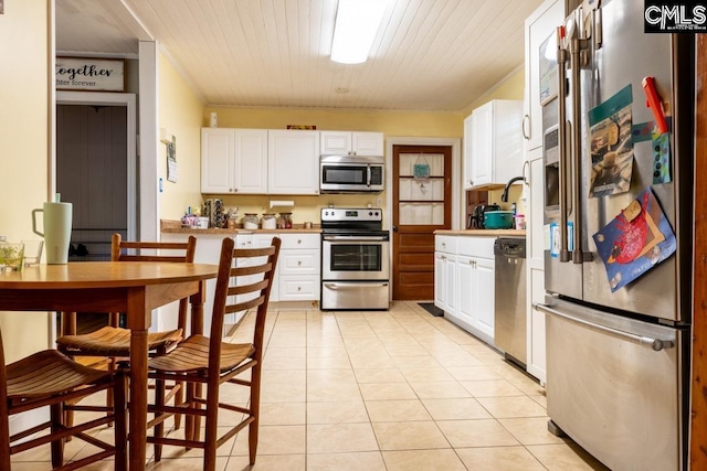 kitchen with stainless steel appliances, white cabinetry, light tile patterned floors, and wood ceiling