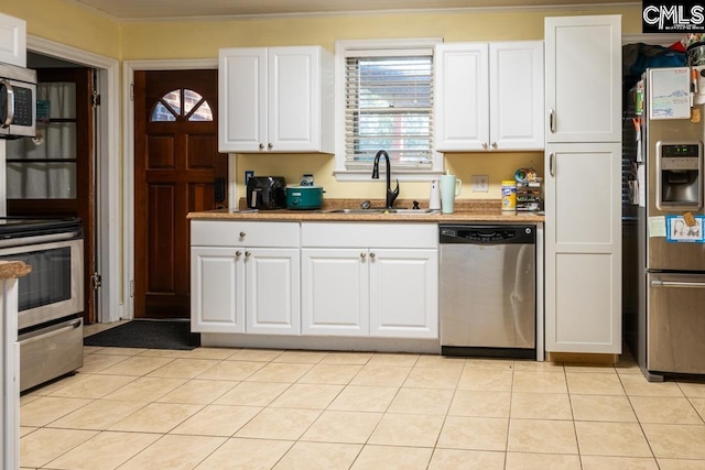 kitchen with light tile patterned floors, appliances with stainless steel finishes, sink, and white cabinets