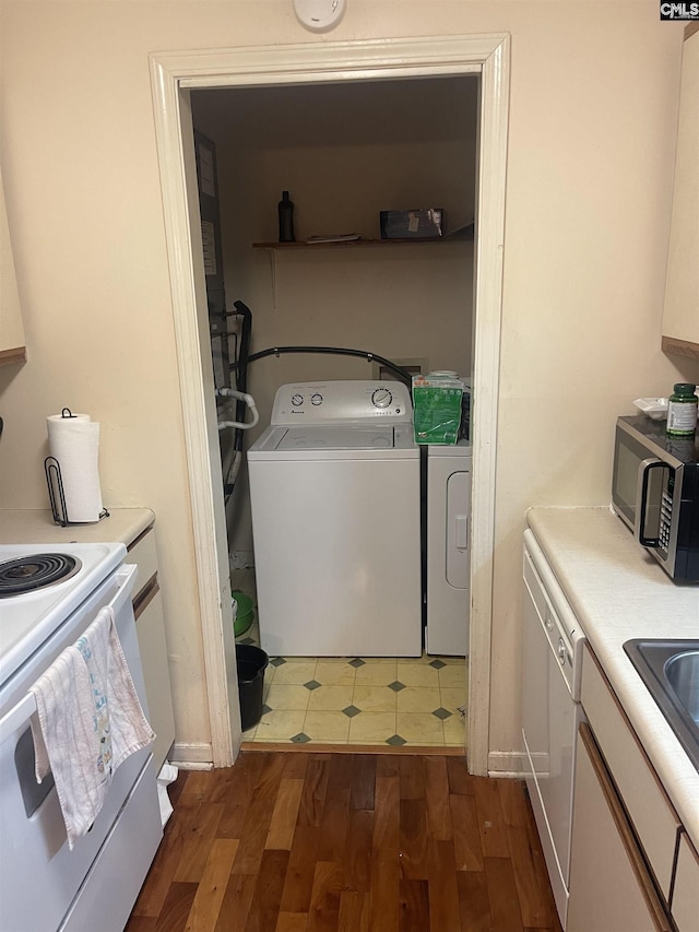 clothes washing area with dark hardwood / wood-style flooring and washing machine and clothes dryer