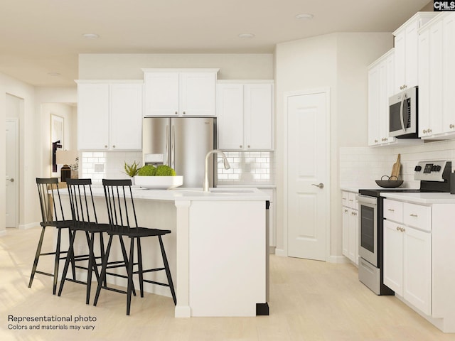 kitchen with backsplash, stainless steel appliances, a kitchen breakfast bar, an island with sink, and white cabinets