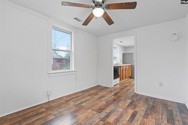 empty room with dark wood-type flooring, ceiling fan, a healthy amount of sunlight, and sink