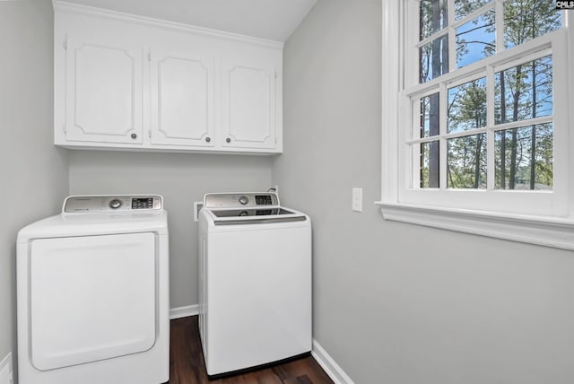 washroom featuring dark wood-type flooring, washer and clothes dryer, and cabinets