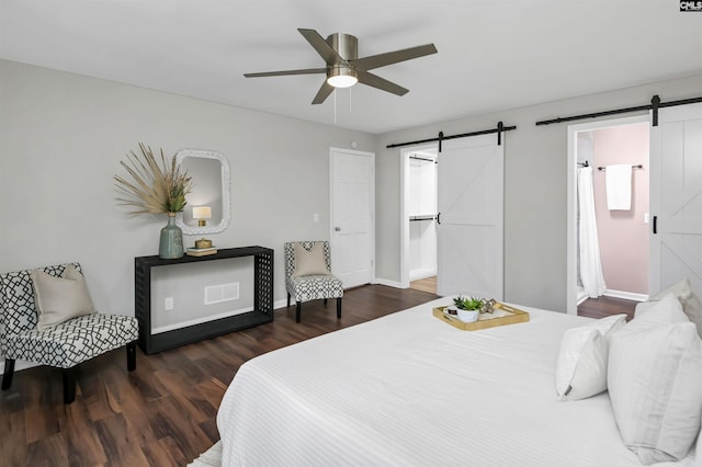 bedroom featuring dark wood-type flooring, a barn door, and ceiling fan