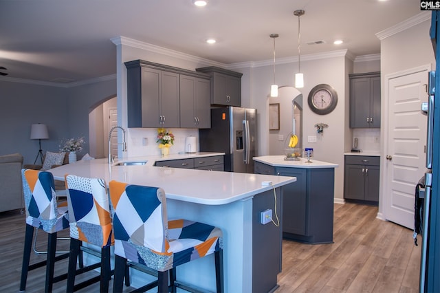 kitchen featuring decorative light fixtures, sink, stainless steel fridge, a kitchen bar, and kitchen peninsula