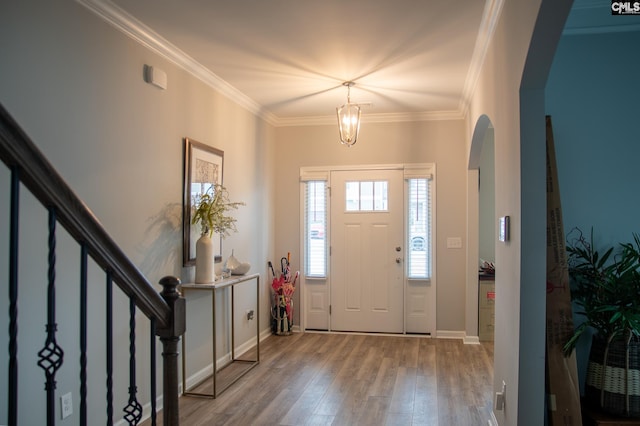 foyer entrance with crown molding, a chandelier, and light wood-type flooring