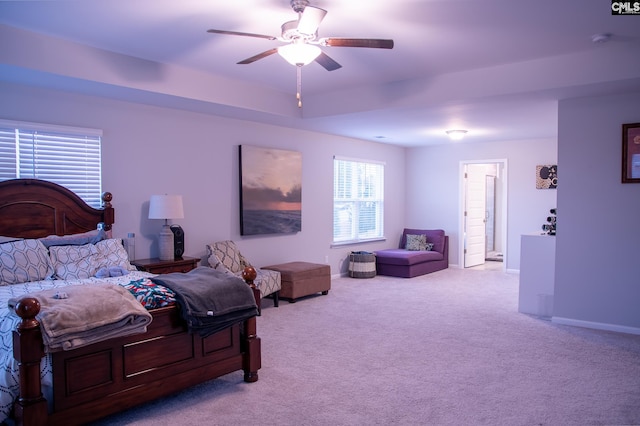 carpeted bedroom featuring ceiling fan and a tray ceiling