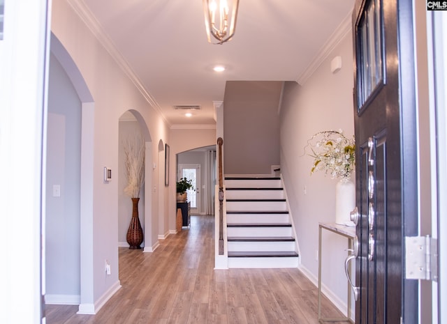 entryway with ornamental molding and light hardwood / wood-style floors