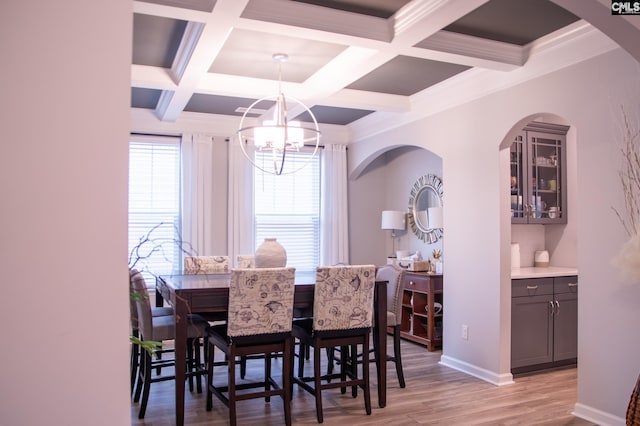 dining room featuring coffered ceiling, a notable chandelier, light hardwood / wood-style floors, crown molding, and beam ceiling