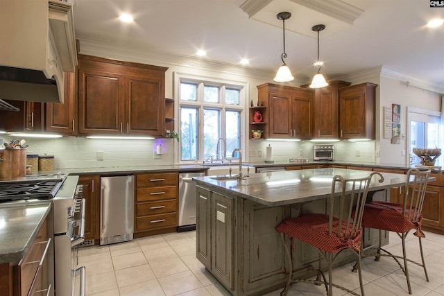 kitchen featuring crown molding, appliances with stainless steel finishes, a kitchen island, and dark stone counters