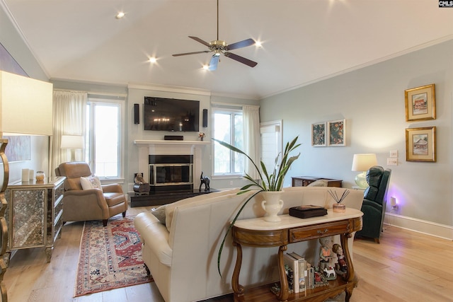 living room with ornamental molding, lofted ceiling, ceiling fan, and light hardwood / wood-style floors