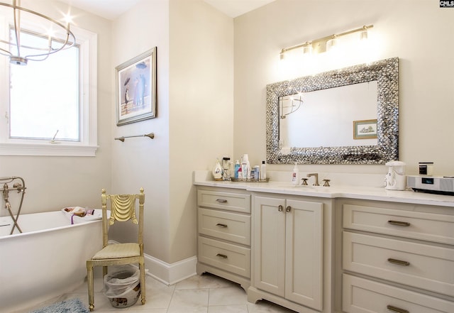 bathroom with an inviting chandelier, tile patterned floors, vanity, and a tub