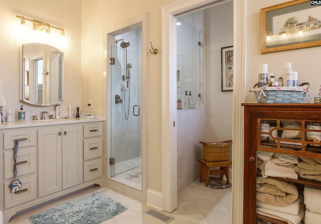 bathroom with tile patterned floors, a shower with shower door, and vanity