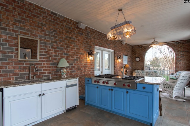 kitchen with brick wall, blue cabinetry, white cabinets, and decorative light fixtures