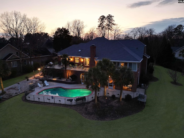 pool at dusk featuring a yard and a patio area