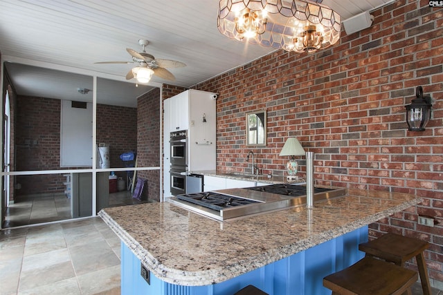 kitchen with brick wall, a breakfast bar, sink, and stone counters