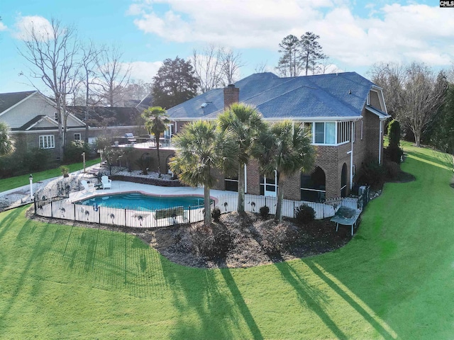 rear view of property with a fenced in pool and a yard